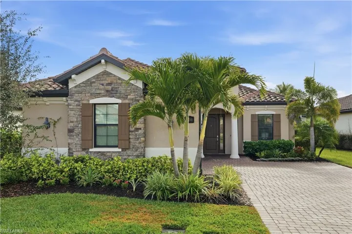 View of front of house with stone siding, a tiled roof, a front lawn, and stucco siding