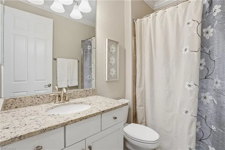 Bathroom with ornamental molding, vanity, a shower with curtain, and a textured wall