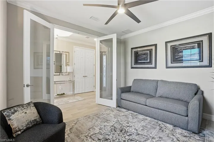 Living area with light wood finished floors, ornamental molding, french doors, and ceiling fan
