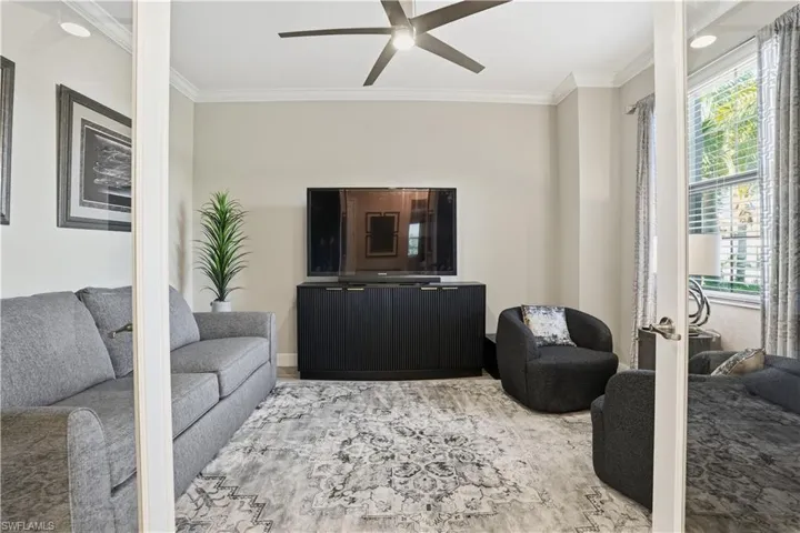 Living room featuring ornamental molding, a ceiling fan, and wood finished floors