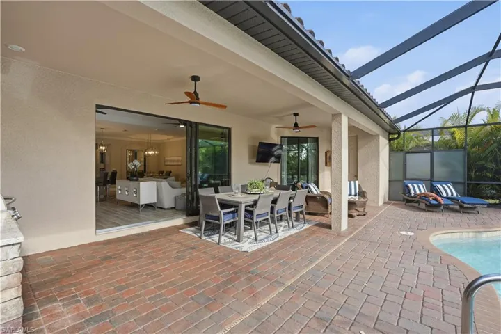 View of patio / terrace featuring a sunroom, outdoor dining space, a lanai, an outdoor pool, and ceiling fan