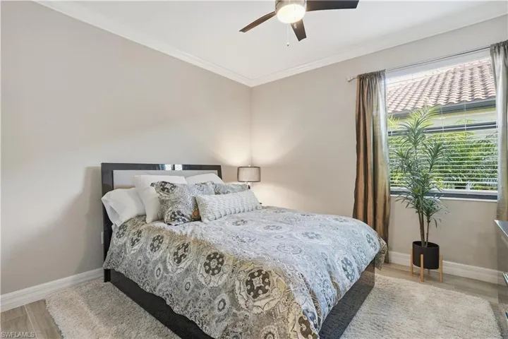 Bedroom with ornamental molding, light wood-style flooring, and a ceiling fan