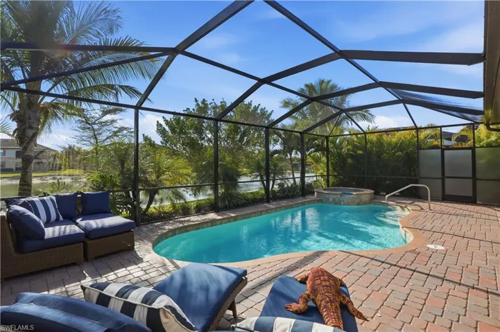 Relaxing pool / spa with a sunroom, a water view, a lanai, and a patio area