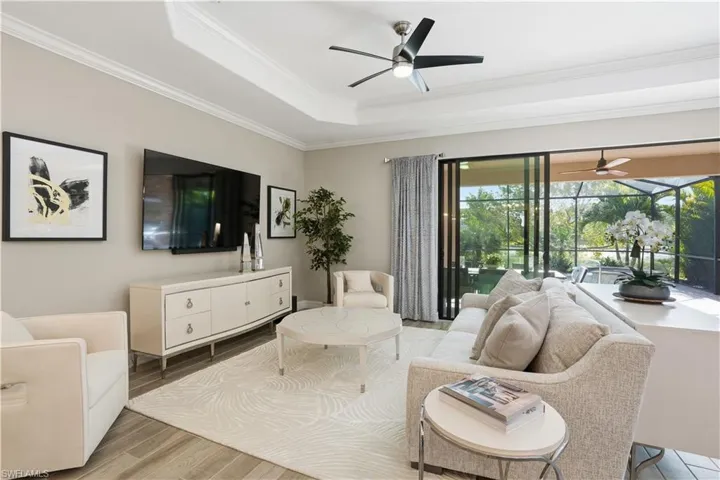 Living area featuring ceiling fan, a sunroom, crown molding, wood finished floors, and a raised ceiling