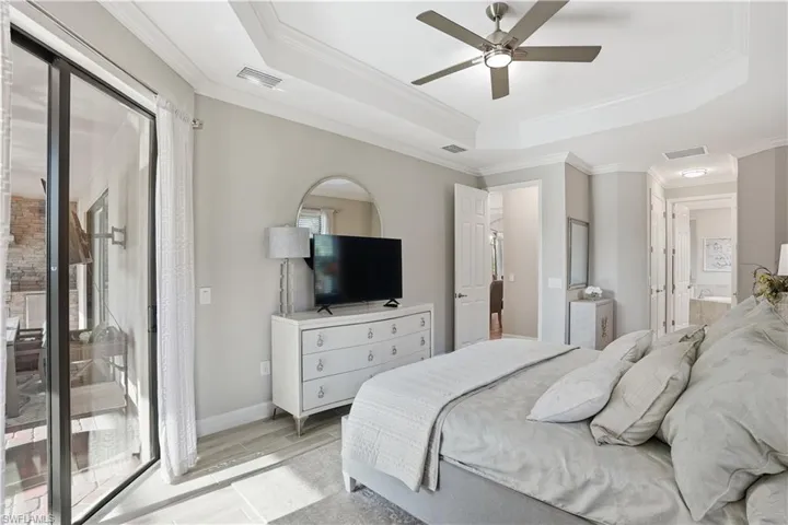 Bedroom with a raised ceiling, access to exterior, ornamental molding, ceiling fan, and wood finish floors