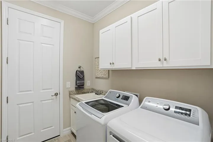 Laundry area featuring ornamental molding, cabinet space, and separate washer and dryer