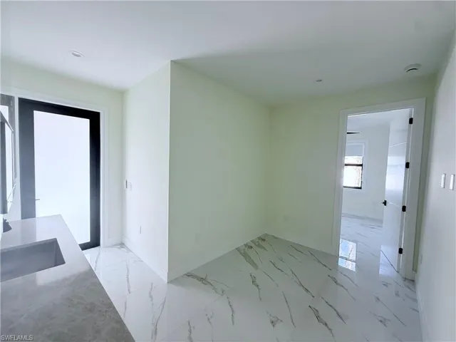 Unfurnished dining area with baseboards and light marble finish floors