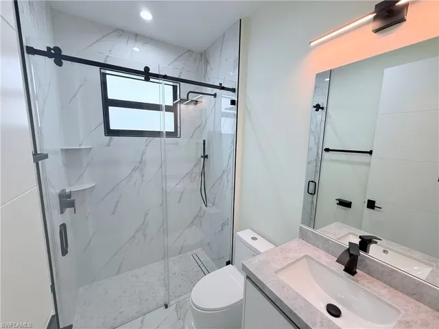 Bathroom featuring vanity and a marble finish shower