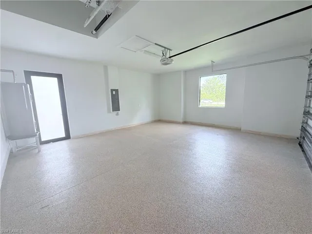 Unfurnished room featuring dark speckled floor, water heater, and electric panel