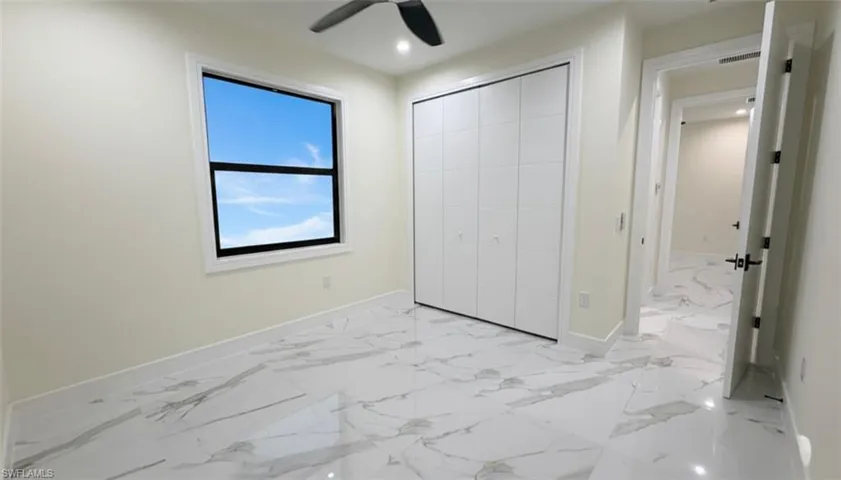 Unfurnished bedroom featuring light marble finish floors, ceiling fan, a closet, and recessed lighting