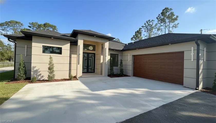 View of front of house featuring a shingled roof, concrete driveway, a garage, and stucco siding