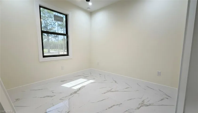 Spare room featuring baseboards and marble look tiles
