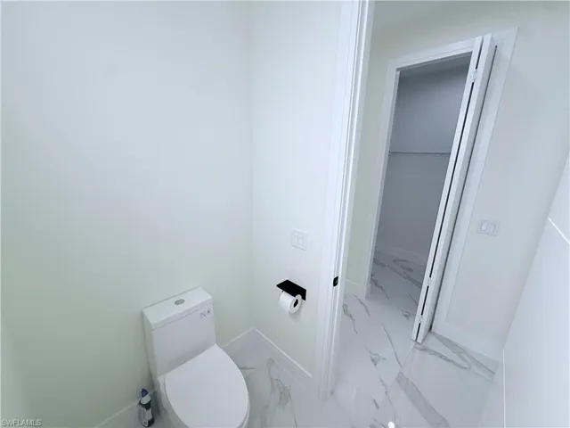 Bathroom featuring a spacious closet and light marble finish floors