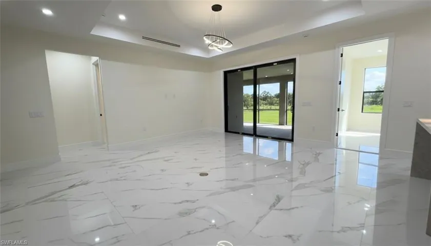 Unfurnished room featuring recessed lighting, a raised ceiling, and light marble finish flooring