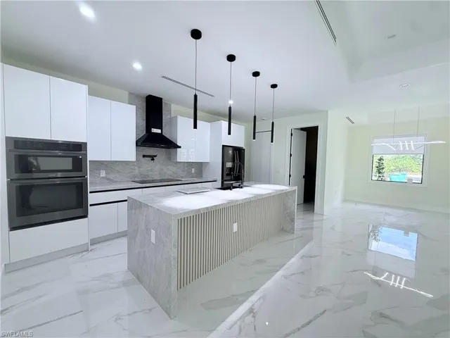 Kitchen with white cabinetry, wall chimney exhaust hood, black appliances, modern cabinets, and decorative backsplash