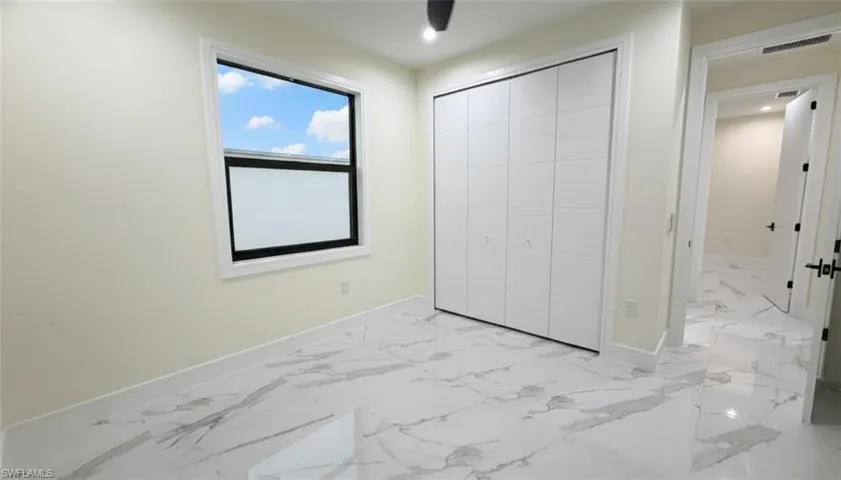 Unfurnished bedroom with light marble finish flooring, a closet, and a ceiling fan