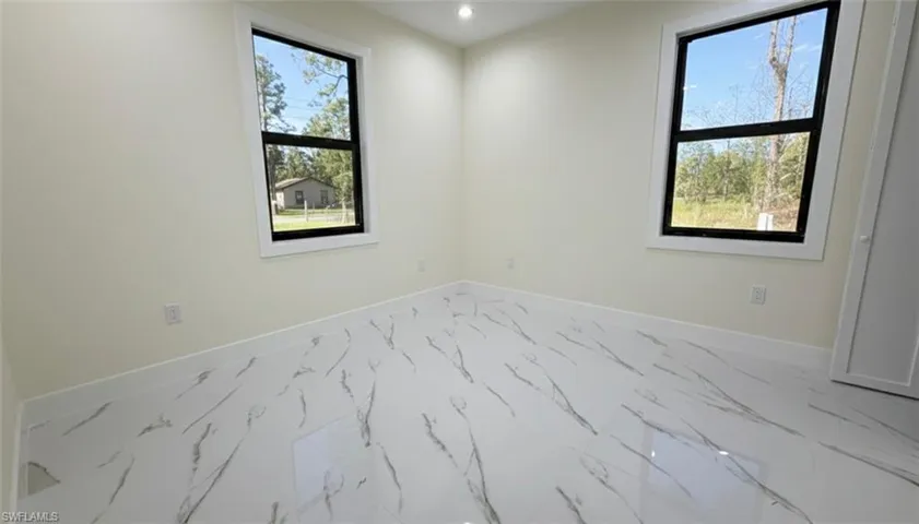 Unfurnished room with marble look tiles and recessed lighting