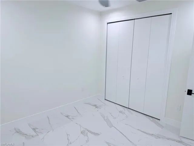 Unfurnished bedroom with a closet and light marble finish flooring