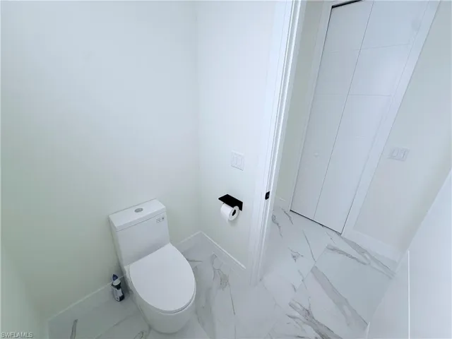 Bathroom featuring toilet and light marble finish flooring