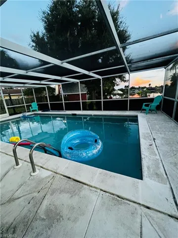 Pool at dusk with a patio area and a lanai