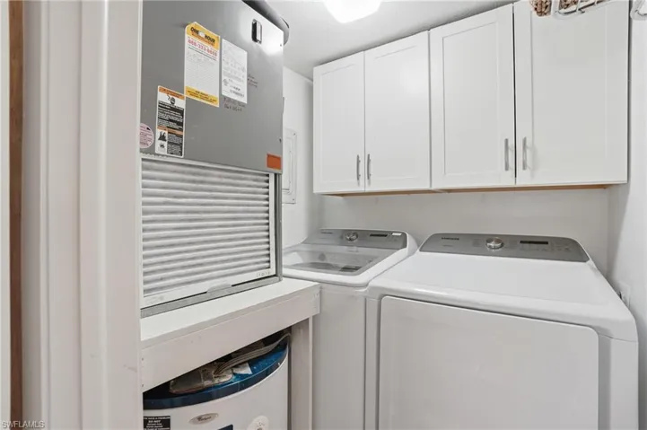 Dedicated laundry area featuring white shaker-style cabinetry, overhead lighting, and white walls