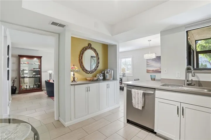 Modern kitchen featuring white cabinetry, light countertops, and a stainless steel sink with a gooseneck faucet