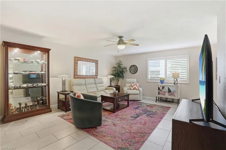 Expansive living area featuring light-toned tile flooring, a ceiling fan with integrated lighting, and neutral wall tones