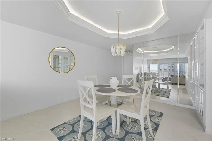 Dining room featuring a tray ceiling, light tile patterned floors, and a chandelier