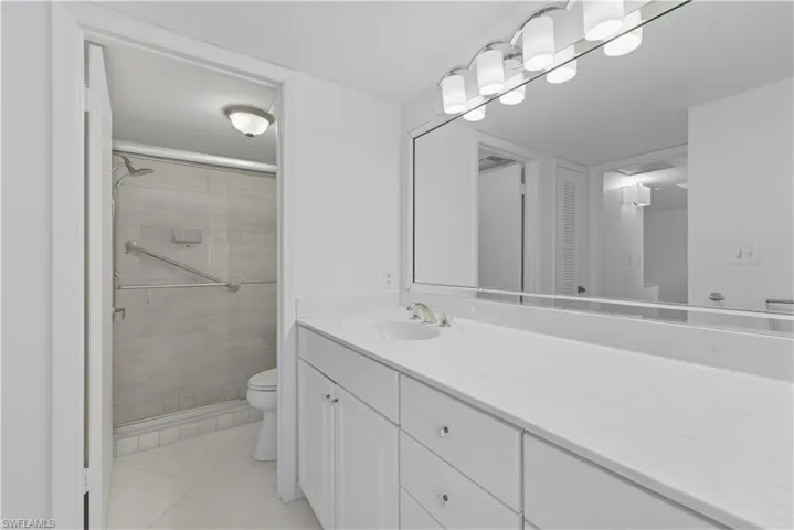 Full bath with vanity, a stall shower, light tile patterned floors, and a closet