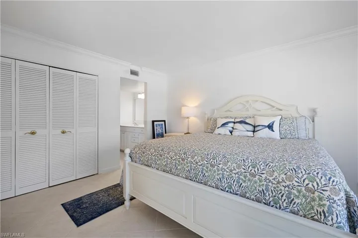 Tiled bedroom featuring crown molding, a closet, and connected bathroom