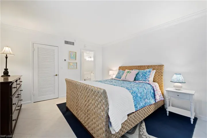 Bedroom with crown molding, light tile patterned floors, and connected bathroom
