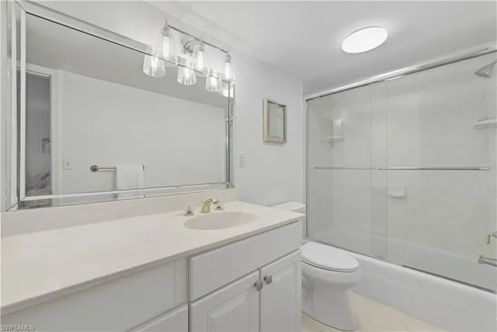 Bathroom with enclosed tub / shower combo, vanity, and light tile patterned floors