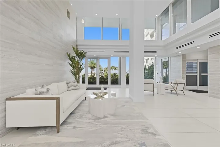 Living room with healthy amount of natural light, a high ceiling, light tile patterned floors, and recessed lighting