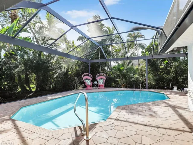 Paver pool deck with saltwater heated pool, panoramic screen enclosure & lush landscaping for privacy