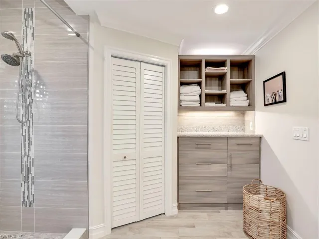 Primary bathroom w/ toilet closet & separate shelving area & cabinetry for towels, etc.