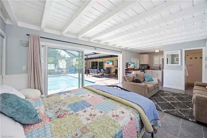 Tiled bedroom with access to outside, a sink, wainscoting, and beam ceiling