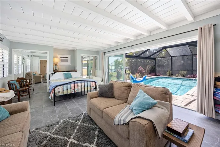 Bedroom with access to exterior, a wall mounted AC, a sunroom, and beamed ceiling