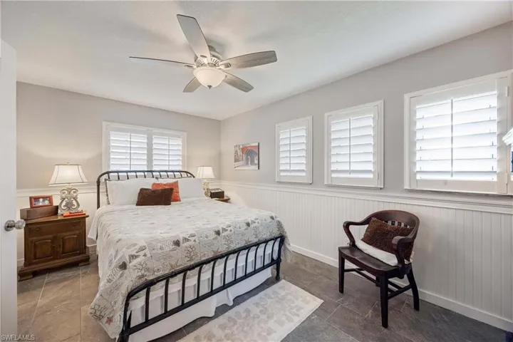 Bedroom featuring a ceiling fan and a wainscoted wall