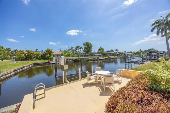 View of dock featuring a water view, fence, and boat lift