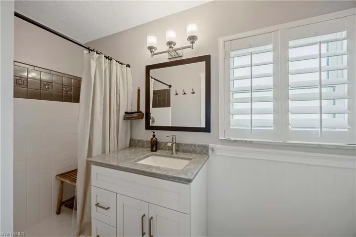 Bathroom featuring vanity, a textured ceiling, a shower with shower curtain, and a healthy amount of sunlight