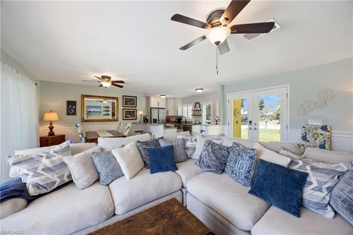 Living area featuring french doors, a ceiling fan, and a wainscoted wall