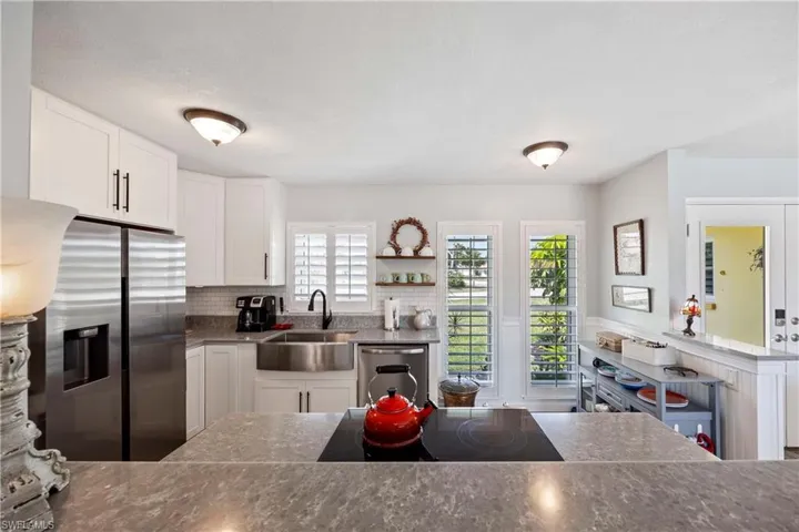 Kitchen with open shelves, white cabinets, a sink, appliances with stainless steel finishes, and backsplash