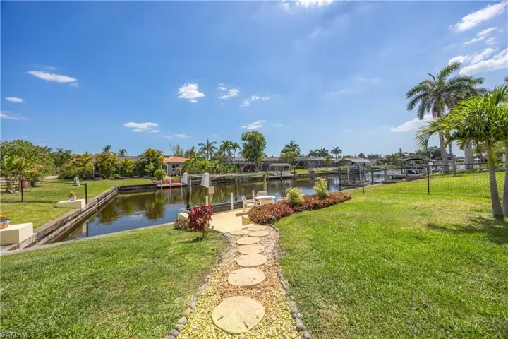 Dock area featuring a lawn, fence, and a water view