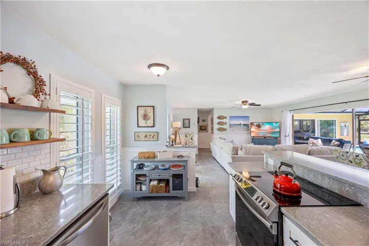Kitchen featuring open shelves, stone countertops, open floor plan, ceiling fan, and stainless steel electric range