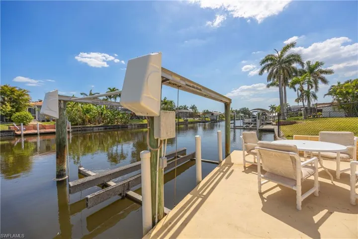 View of dock featuring a water view, fence, and boat lift