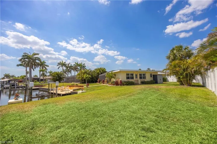 View of yard featuring a dock, a water view, and fence