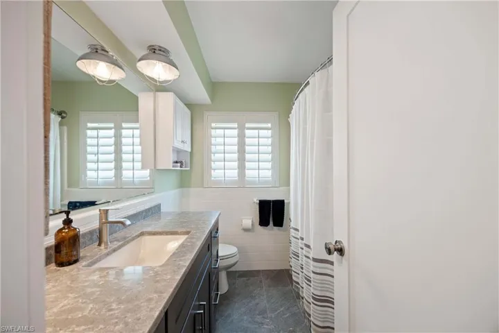 Full bath featuring a healthy amount of sunlight, tile walls, vanity, and toilet