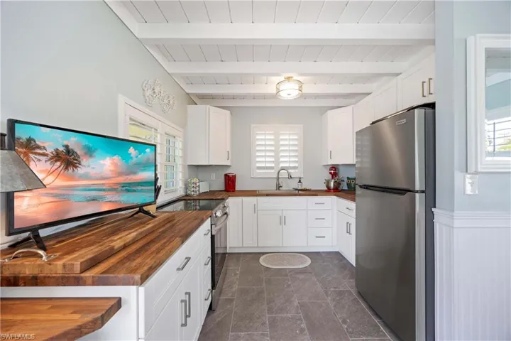 Kitchen with white cabinets, beam ceiling, stainless steel appliances, and butcher block countertops
