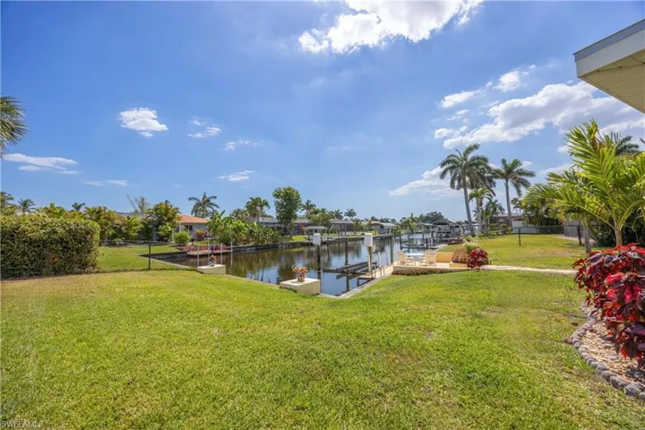 View of dock featuring a lawn, a water view, and fence