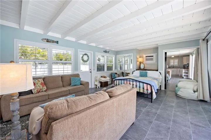 Bedroom featuring a wall mounted AC and beamed ceiling